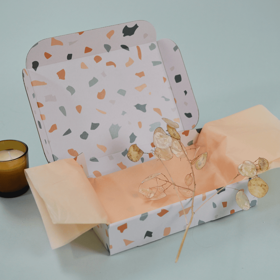 Une feuille de papier de soie orange pastel déposée dans une boîte postale